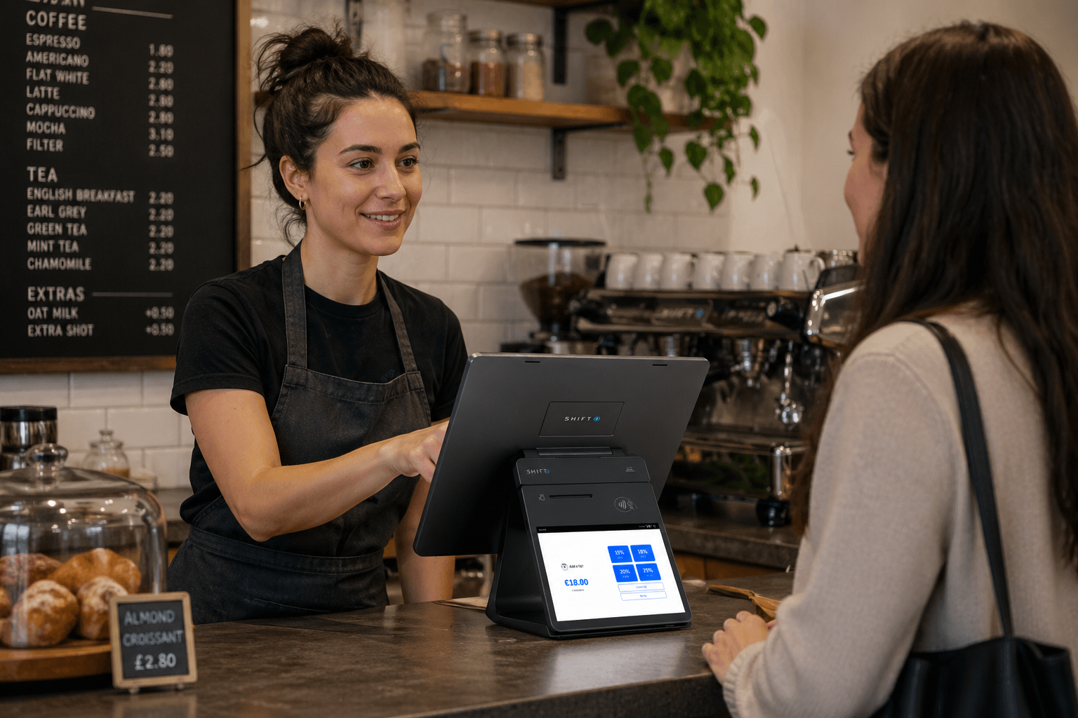 A café worker takes a customer payment using an ithPOS SkyTab POS terminal with tip selection on screen